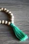 Braccialetto di perle in legno non trattato con frangia in cotone. Colore verde