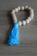 Braccialetto di perle in legno non trattato con frangia in cotone. Colore blu