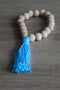 Braccialetto di perle in legno non trattato con frangia in cotone. Colore blu
